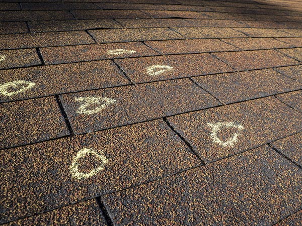 Hail-Damage-Roof-Cartersville-GA-Georgia-2 | Rise Residential Roofing Close-up of brown shingles with white chalk circles around spots, likely inspection marks.