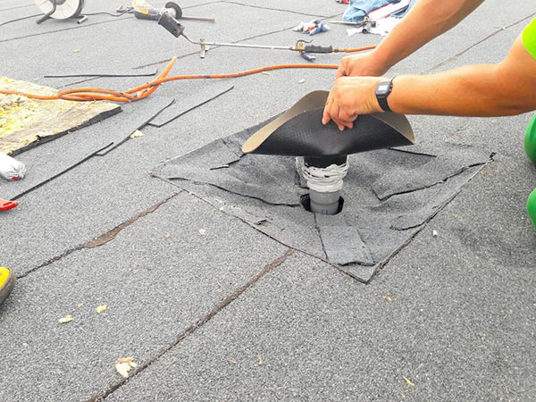 Roof-Leak-Repair-Cartersville-GA-Georgia-1 | Rise Residential Roofing Person installing roof vent flashing on a gray shingle roof; tools and wires scattered nearby.