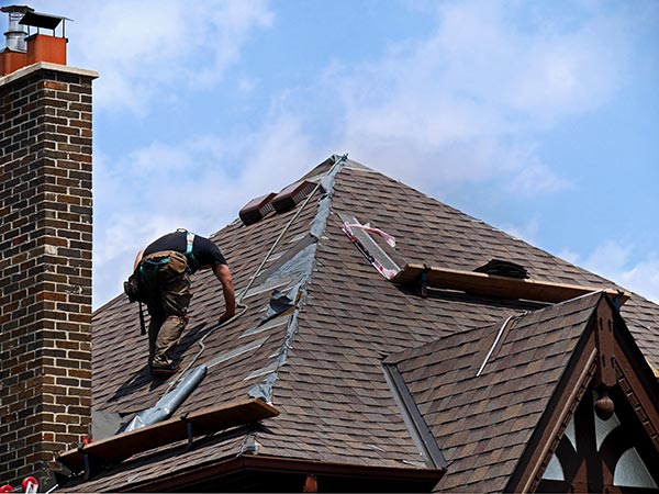 Roof-Repairs-Cartersville-GA-Georgia-1 | Rise Residential Roofing Construction worker on a sloped roof repairing shingles with tools scattered nearby.